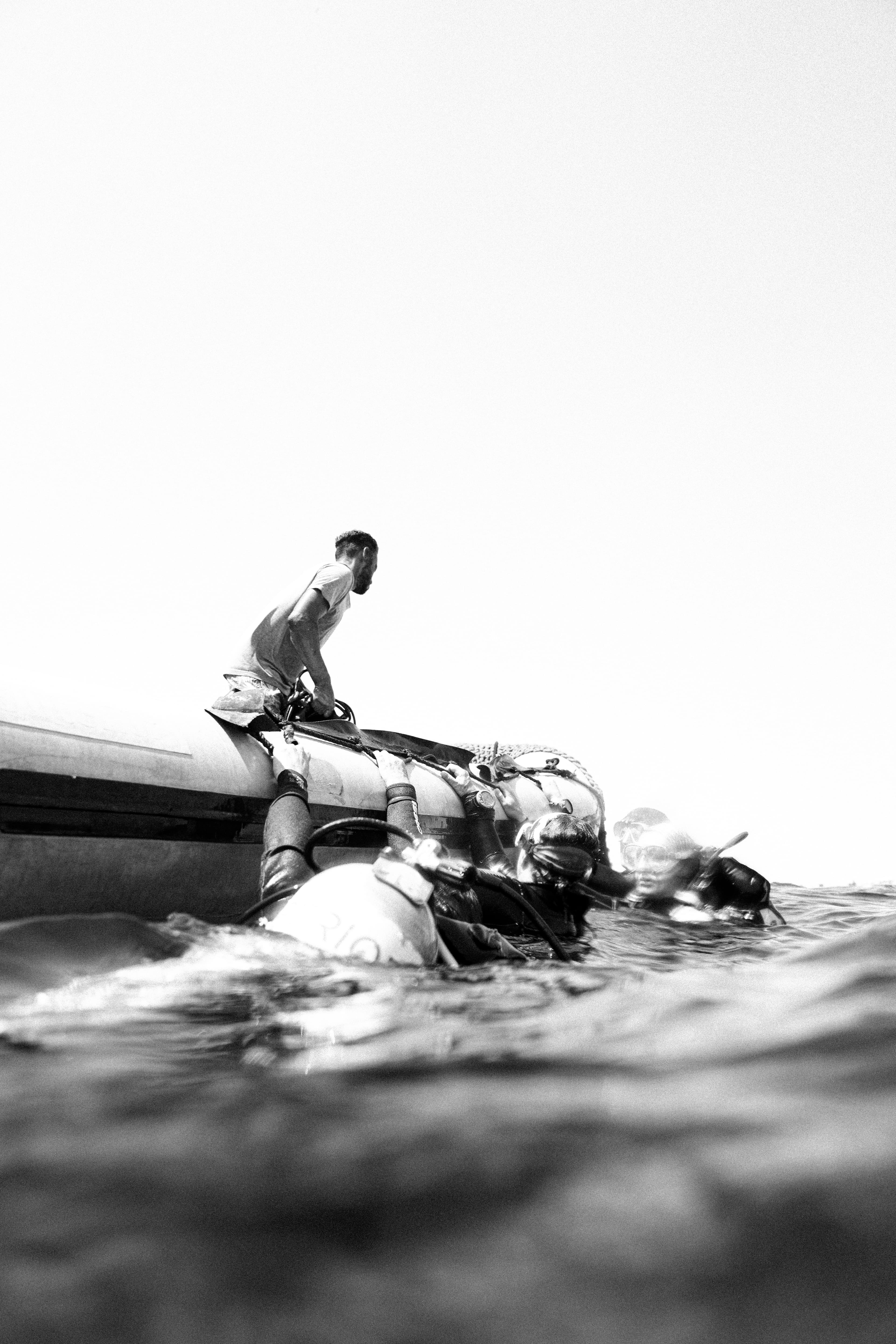 Diver entering the water from a small boat, half above and half below the surface.