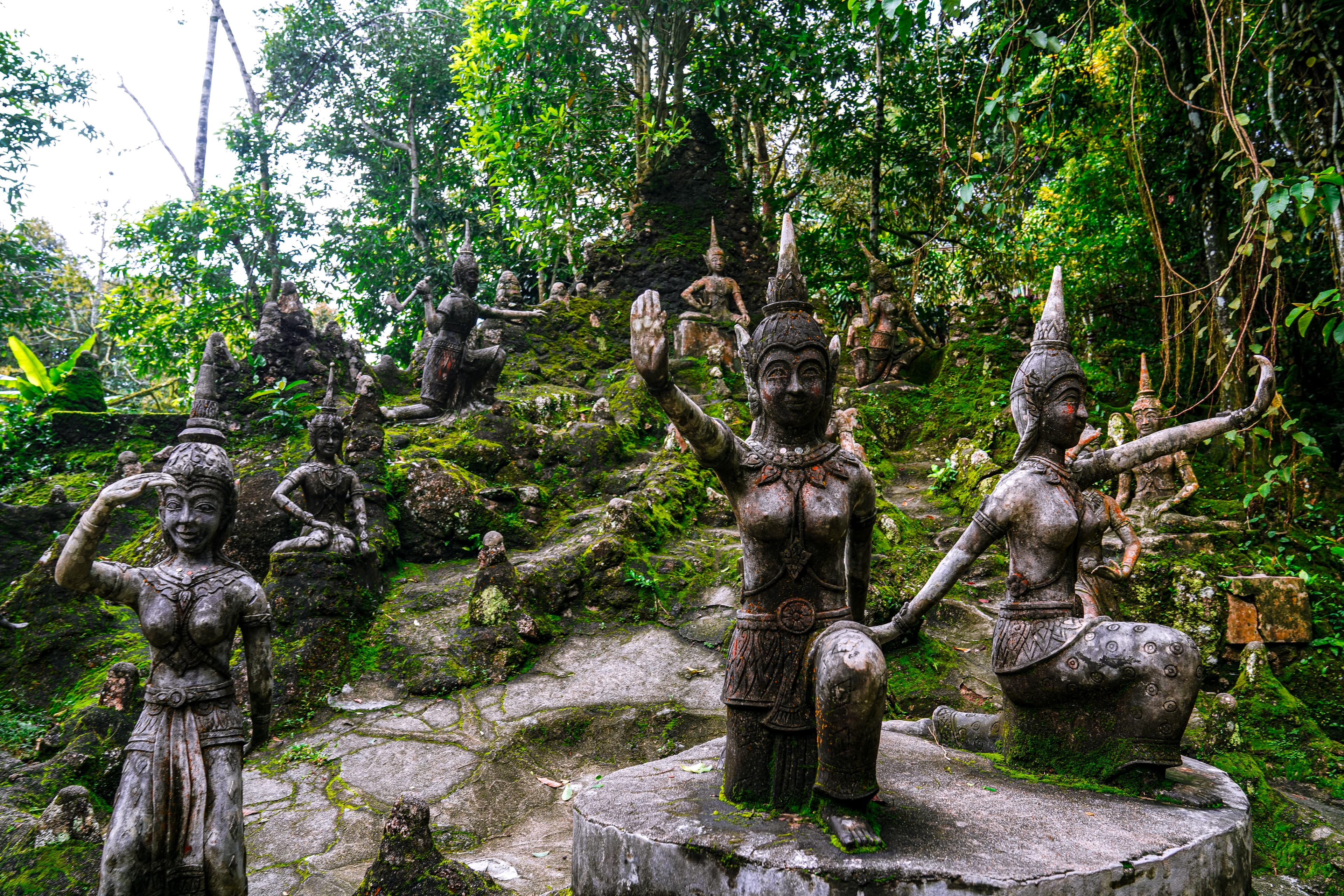 Ancient statues surrounded by lush jungle in Balis Sacred Monkey Forest.
